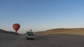 Bright balloons rise above the sand dunes.