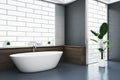 Bright bathroom interior with bathtub, abstract windows and reflections on concrete flooring. Royalty Free Stock Photo