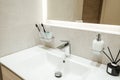 Bright bathroom interior with white sink and toothbrushes, flavoring and liquid soap on it Royalty Free Stock Photo