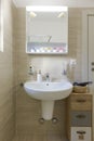 Bright bathroom with large beige tiles. Front view of sink with mirror above Royalty Free Stock Photo