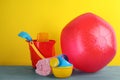 Bright beach ball, blanket and sand toys on light blue wooden table against yellow background Royalty Free Stock Photo