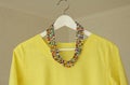 Bright beads of Murano glass hang on the background of a yellow summer dress. Summer jewelry, summer clothes