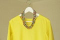 Bright beads of Murano glass hang on the background of a yellow summer dress. Summer jewelry, summer clothes