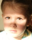 Bright beam of light illuminates part of the little girl`s face and shadow covering her beautiful eyes depicting a face mask.