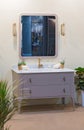 Bright beautiful bathroom with square mirror, gray cabinet with drawers. green flowers and golden tap and decorations. Classic Art Royalty Free Stock Photo