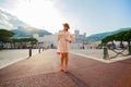 a bright beautiful girl in a light dress and hat walks along the streets of old town of Monaco in sunny weather, a Royalty Free Stock Photo