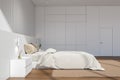 Bright bedroom interior with empty white wall, large bed, bedside Royalty Free Stock Photo