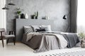 Stylish standing lamp next to a bed in a monochromatic grey bedr