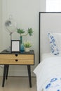 Bedroom interior with striped pillow on bed and bedside table lamp with picture frame on it.