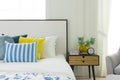 Bedroom interior with striped pillow on bed and bedside table lamp with picture frame on it. Royalty Free Stock Photo