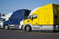 Bright big rig semi trucks standing in row on truck stop in sunny day Royalty Free Stock Photo