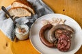 Bright and black pudding, sausage on plate, lard and greaves, bread and towel on table