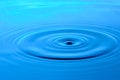 Bright blue background with diverging circles from dropped drop on surface water Royalty Free Stock Photo