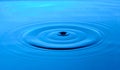 Bright blue background with diverging circles from dropped drop on surface water Royalty Free Stock Photo