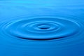 Bright blue background with diverging circles from dropped drop on surface water Royalty Free Stock Photo