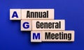 On a bright blue background, light wooden blocks and cubes with the text AGM Annual General Meeting Royalty Free Stock Photo
