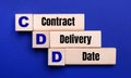 On a bright blue background, light wooden blocks and cubes with the text CDD Contract Delivery Date Royalty Free Stock Photo