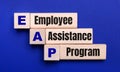 On a bright blue background, light wooden blocks and cubes with the text EAP Employee Assistance Program