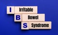 On a bright blue background, light wooden blocks and cubes with the text IBS Irritable Bowel Syndrome