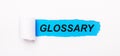 On a bright blue background, white paper with a torn stripe and the text GLOSSARY Royalty Free Stock Photo