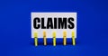 On a bright blue background on yellow clothespins, a white card with the text CLAIMS Royalty Free Stock Photo