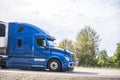 Bright blue big rig long hauler semi truck with refrigerated semi trailer and grille guard driving on the road for delivery Royalty Free Stock Photo