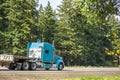 Bright blue big rig semi truck with aluminum step down semi trailer driving on the green highway Royalty Free Stock Photo