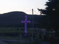 Bright blue cross at dusk in rural countryside