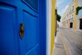 Bright blue door on a wall in a narrow street with colorful buildings Royalty Free Stock Photo