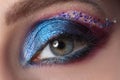 Bright blue evening eyelid makeup with multi-colored sparkles