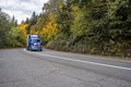 Bright blue fresh big rig semi truck transporting frozen cargo in reefer semi trailer driving on the curved road through the Royalty Free Stock Photo