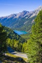 Bright blue mountain lake under blue sky with woods, stones and snow Royalty Free Stock Photo