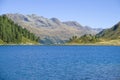 Bright blue mountain lake under blue sky with woods, stones and snow Royalty Free Stock Photo