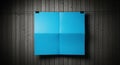 Blue Paper Folded into Four Sections Hanging on a Wooden Wall Royalty Free Stock Photo