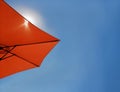 Bright blue sky background with a red beach umbrella. Theme of tourism, relax, vacation, holiday, repose, take a rest by the sea. Royalty Free Stock Photo