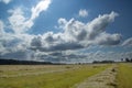 Bright blue sky and clouds of different shapes and colors. Downstairs is a field after harvesting wheat. In the woods Royalty Free Stock Photo