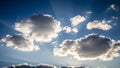 Bright blue sky with fluffy white clouds and sun rays breaking through creating a dramatic atmospheric scene Royalty Free Stock Photo