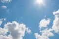 Bright blue sky with sunbeams and fluffy white clouds on a sunny day.