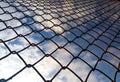 Bright blue sky with white clouds through a metal grid chain fence. Mesh background Royalty Free Stock Photo