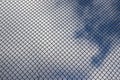 Bright blue sky with white clouds through a metal grid chain fence. Mesh background Royalty Free Stock Photo