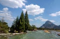 Bright blue sky white clouds, wide rapids river and mountains, pine spruce forest and rocks on river bank, scenic landscape, Royalty Free Stock Photo