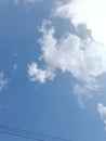 A bright blue sky with wispy white clouds, with two parallel power lines visible at the bottom of the frame. Royalty Free Stock Photo