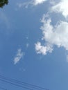 A bright blue sky with wispy white clouds, with two parallel power lines visible at the bottom of the frame. Royalty Free Stock Photo