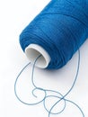 Close up of a bright blue spool of thread with loose strands on a white background sewing Royalty Free Stock Photo