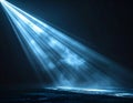 Bright Blue Spotlight Illuminates Dark Stage with Wisps of Smoke and Floating Particles Royalty Free Stock Photo