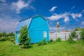 Bright blue summer house, fence and electrical wires on a background of blue sky with white clouds Royalty Free Stock Photo