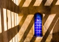 Bright blue tile window on adobe building with shadow pattern
