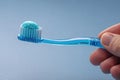Bright blue toothbrush held by hand with mint toothpaste ready for use in a bathroom setting Royalty Free Stock Photo