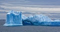 Bright blue and turquoise iceberg in grey southpolar ocean Royalty Free Stock Photo