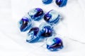 Bright blue washing pods and capsules with liquid detergent for machine laundry on white clothing background. Royalty Free Stock Photo